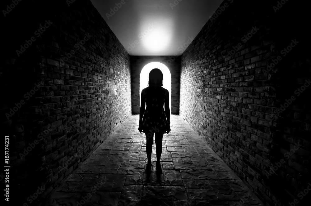 Silhouette of Lonely woman standing in the tunnel and Light at the end of the tunnel.