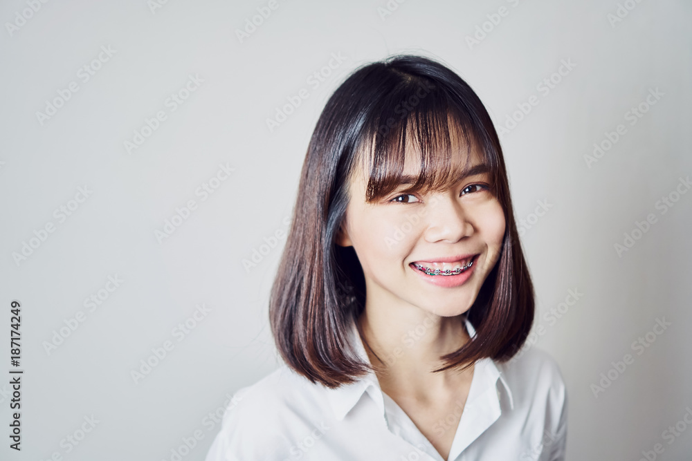 copy space portrait of smiling asian young woman put on the braces, on a gray background gives a soft light. copy space portrait of smiling asian young woman put on the braces, on a gray background gives a soft light.