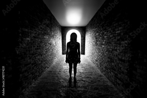 Silhouette of Lonely woman standing in the tunnel and Light at the end of the tunnel.