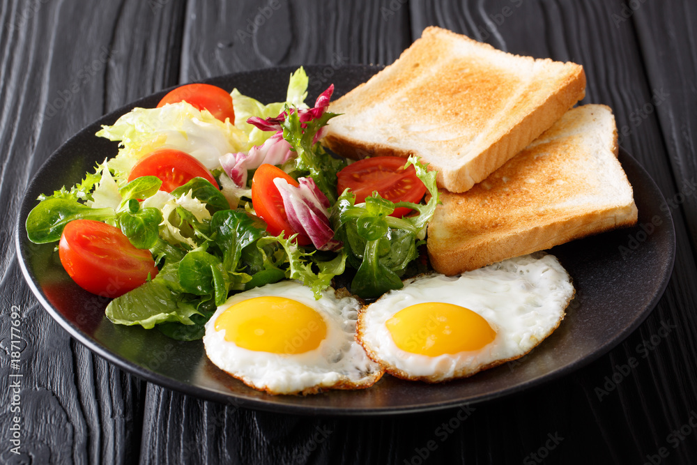 Organic food breakfast: fried eggs with fresh vegetable salad and toast close-up on a plate. horizontal