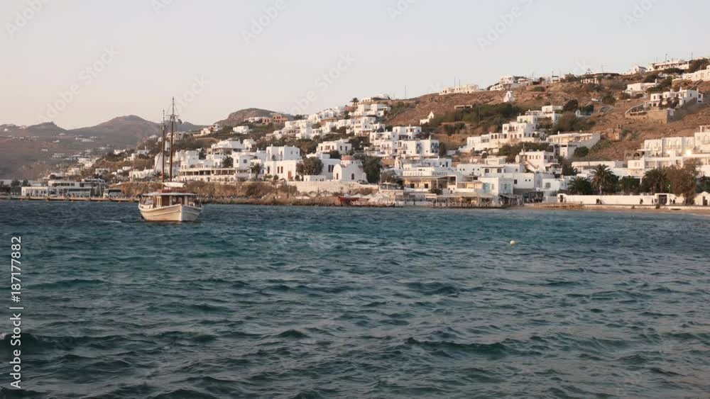 wide angle view of a sailing boat and the harbor at chora, mykonos in the late afternoon wide angle view of a sailing boat and the harbor at chora, mykonos in the late afternoon