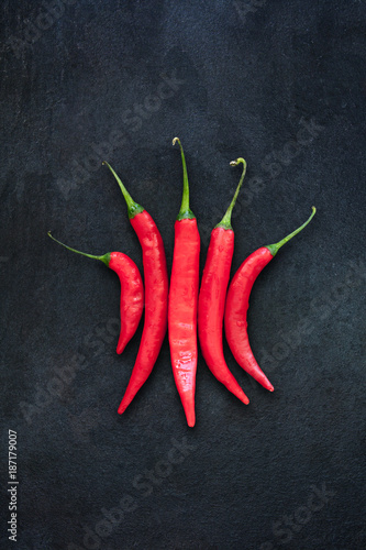 Group of five red chili peppers isolated on dark gray slate