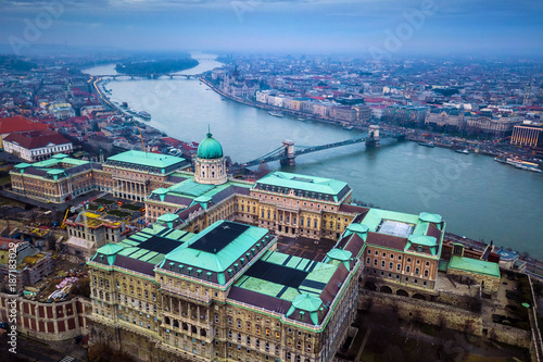 Budapest, Hungary - Aerial drone skyline view of Buda Castle Royal Palace with Szechenyi Chain Bridge and Parliament of Hungary on a cloudy winter day