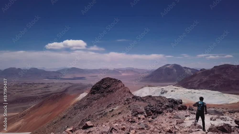 Skyrunner standing on the summit and looking to the mountain chain in the Atacama desert. Aerial view of mountaineer contemplating the sky, peaks and volcanoes. 4k
Skyrunner standing on the summit and looking to the mountain chain in the Atacama desert. Aerial view of mountaineer contemplating the sky, peaks and volcanoes. 4k