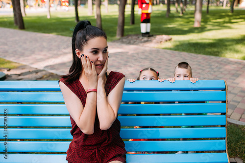 Children playing hide and seek game with mother in the park. Family leisure. photo