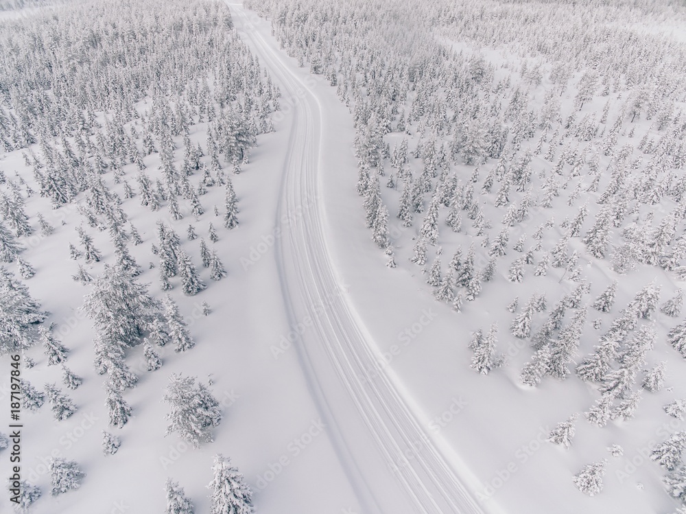 Naklejka premium Aerial view of the road in the winter snow forest in Finland