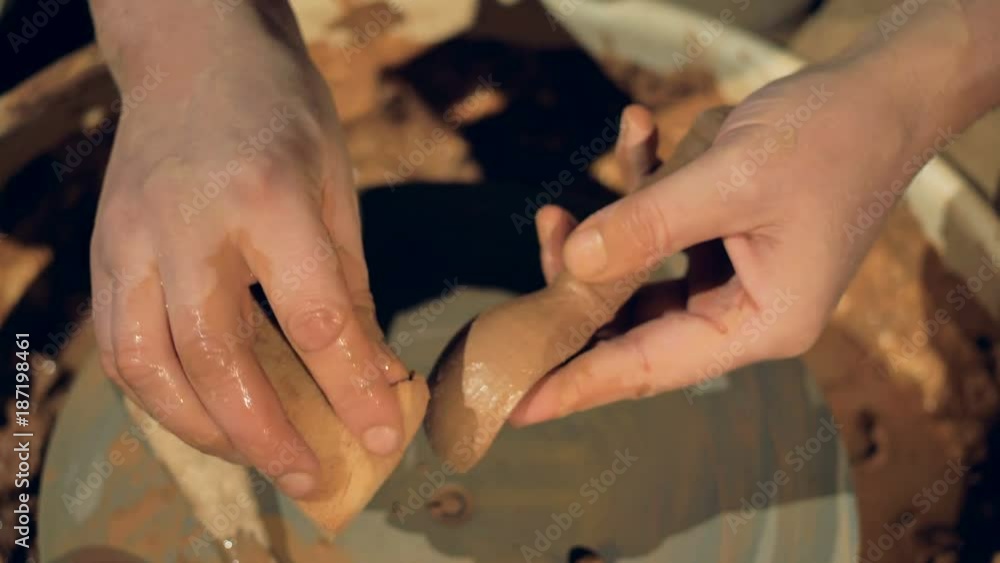 A potter covers a clay spoon with water. A potter covers a clay spoon with water.