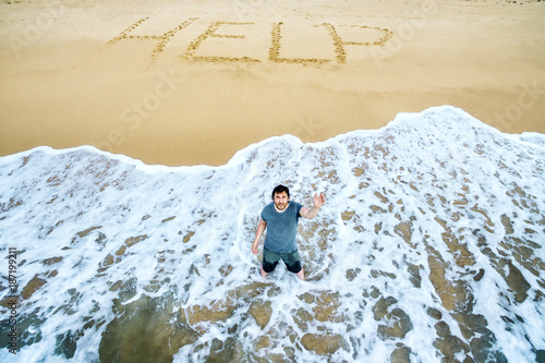 Castaway and lost in uninhabited island, survivor is calling for help on deserted beach photo