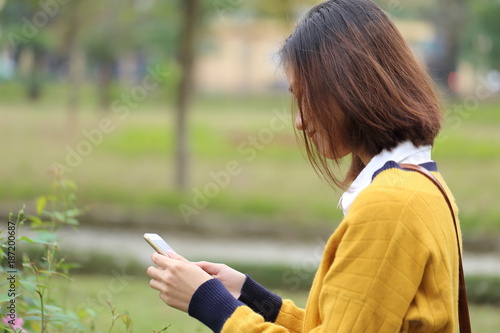 スマートフォンで花の写真を撮影する女性 © kunio