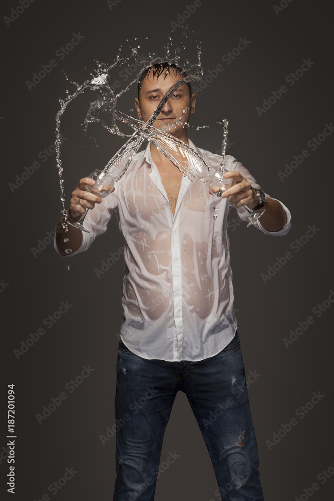 Portrait of a wet young man with two glasses in the studio