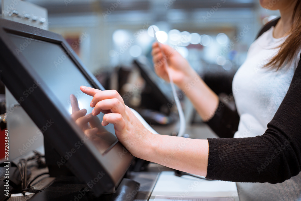 Young woman hands scaning / entering discount / sale on a receipt, touchscreen cash register, market / shop