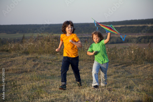 Children playing kite on summer sunset meadow