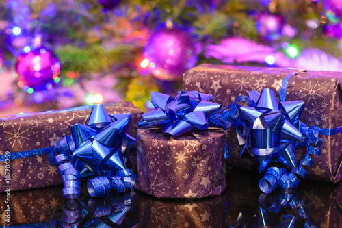 Christmas gifts wrapped in purple wrapping paper bound with blue ribbon and ornament photo