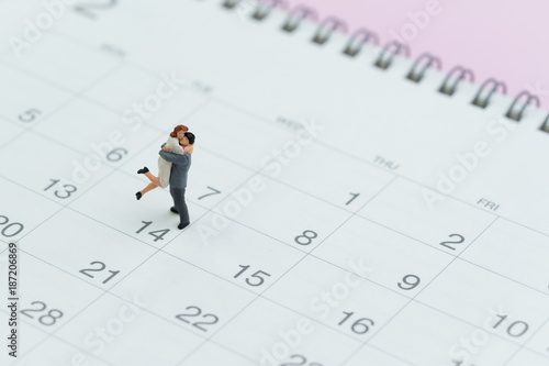 Valentines day reminder with lovely miniature couple standing on 14 Feb calendar on pink background © Nuthawut