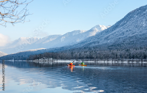 two people kayaking in the winter among mountains