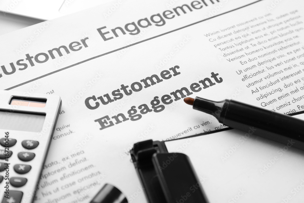 Obraz premium Newspaper with text CUSTOMER ENGAGEMENT on table