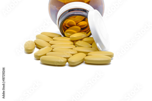 Vitamin C tablets spilling out of a glass bottle on white background for healthcare and medical concept