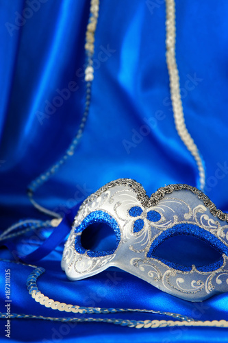 Image of elegant venetian mask over blue silk background.