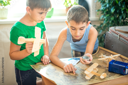 Happy children boys with a toy airplane in hand, explore the map below to travel to new adventures.