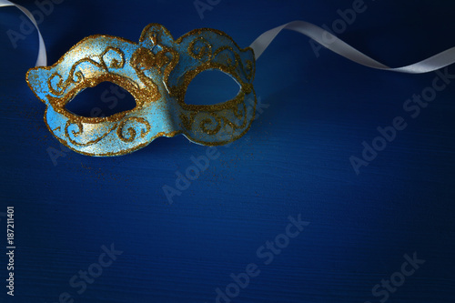 Image of elegant blue and gold venetian, mardi gras mask over blue background.