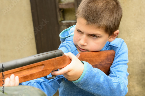 A little boy shooting from an air rifle to a target