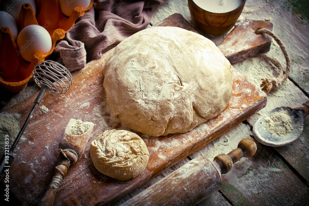Fototapeta premium Dough with flour on an old background in a composition with kitchen accessories