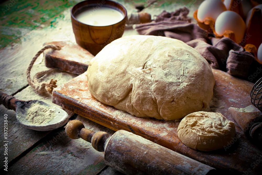 Fototapeta premium Dough with flour on an old background in a composition with kitchen accessories