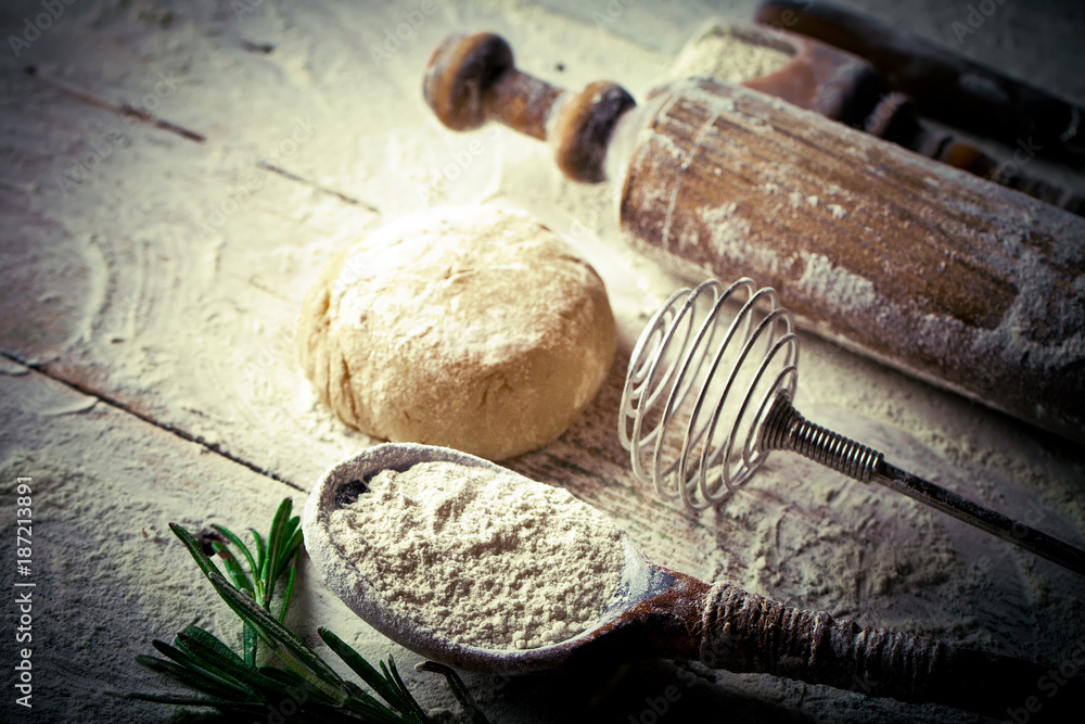 Fototapeta premium Dough with flour on an old background in a composition with kitchen accessories