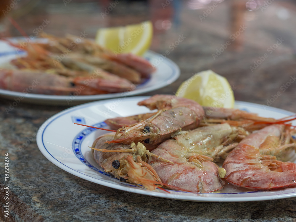 close up boiled giant red prawns with lemon and garlic on plate on marblel desk