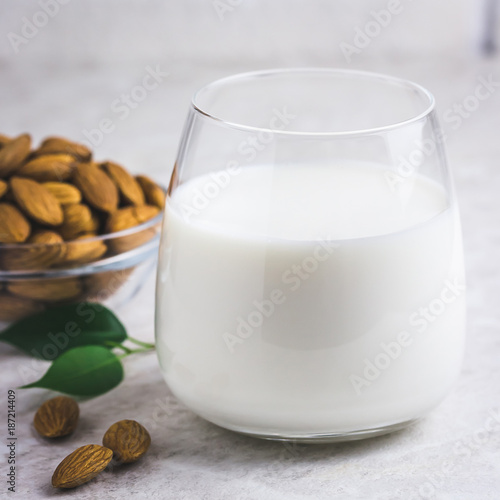 Glass of almond milk and almonds on white marble background. Selective focus, space for text, toned.