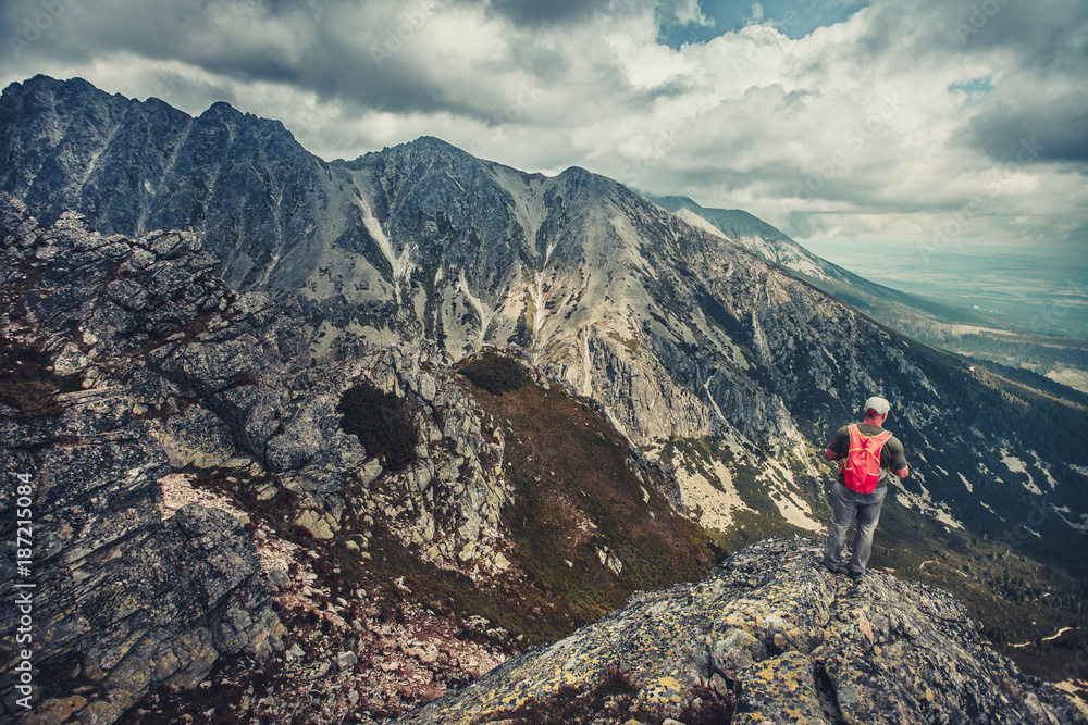A hiker is standing on the edge of the precipice in the Tatra Mountains, Slovakia. Outdoor extreme activity. Unforgettable magnificent panoramic view. Serenity of wild virgin nature.