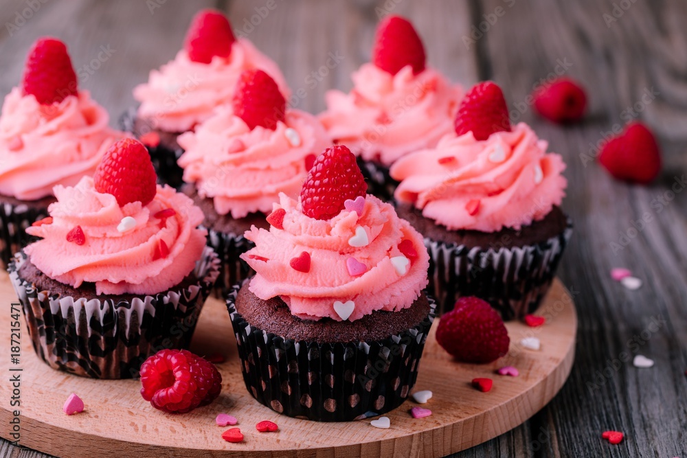 Chocolate cupcakes with pink cream, sugar hearts and fresh raspberries for  Valentine Day