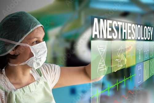 Anesthesiology concept. Doctor using a futuristic touch screen concept computer with medical icons on it. Healthcare operation surgery room on background.