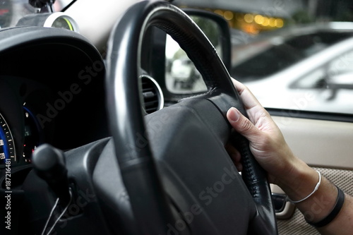 Selective focus on hand of driver on steering wheel of car