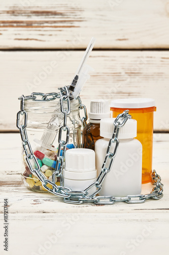 Chains over prohibited medications. Pills, syrups and syringe. Abuse, drug addiction and criminal liability for dealers. © DenisProduction.com