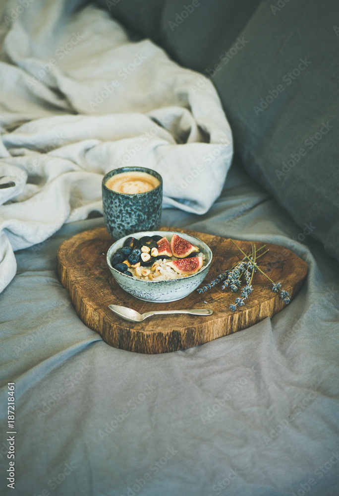 Healthy winter breakfast in bed. Rice coconut porridge with figs, berries and hazelnuts and cup of espresso over rustic wooden board background, copy space. Clean eating, alkiline diet food concept Healthy winter breakfast in bed. Rice coconut porridge with figs, berries and hazelnuts and cup of espresso over rustic wooden board background, copy space. Clean eating, alkiline diet food concept
