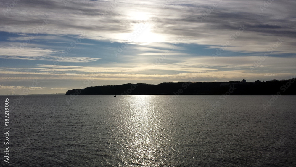 The sun breaks through the clouds over the calm sea The sun breaks through the clouds over the calm sea