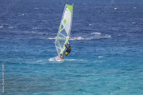 windsurfer on a board under a sail against the background of the sea, wind and waves.