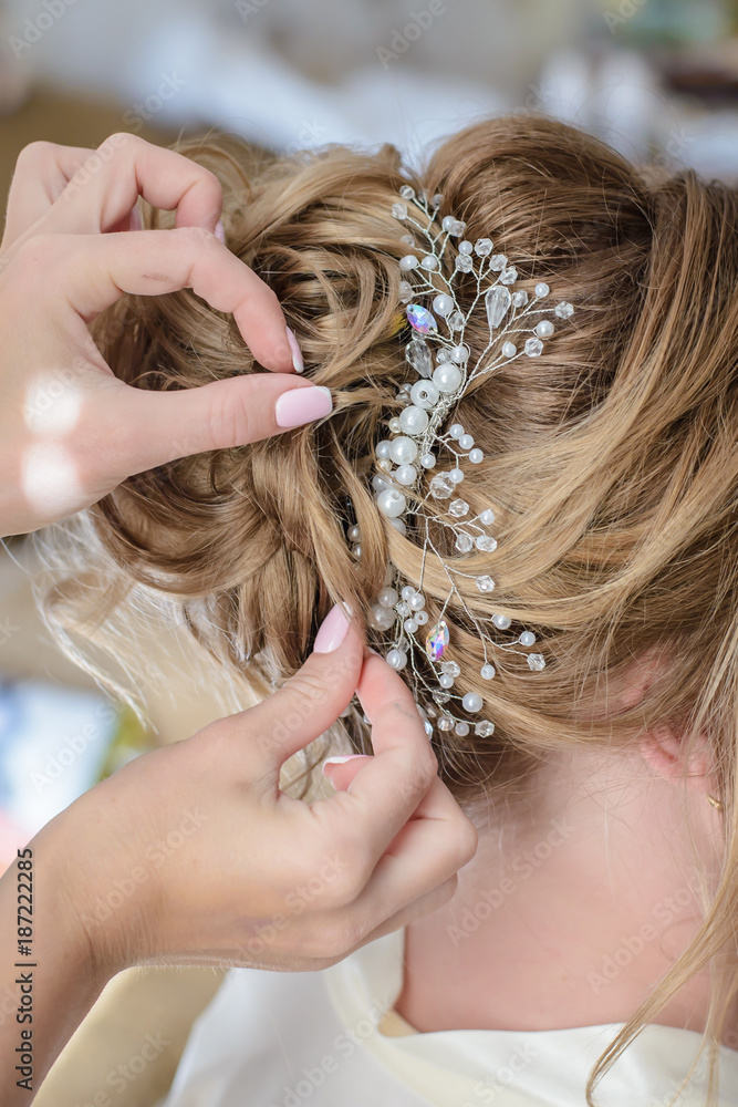 Hairdresser makes a wedding hairstyle with a beautiful decoration