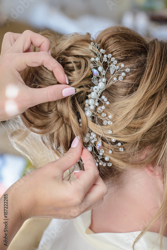 Hairdresser makes a wedding hairstyle with a beautiful decoration