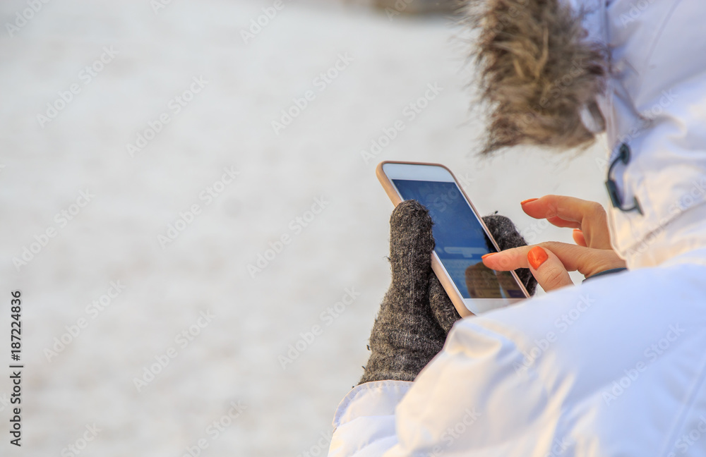 woman writing message on the phone in the street in winter