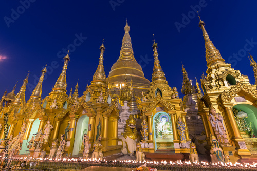 Many small pagodas and statues in front of the gilded Shwedagon Pagoda in Yangon, Myanmar in the evening.