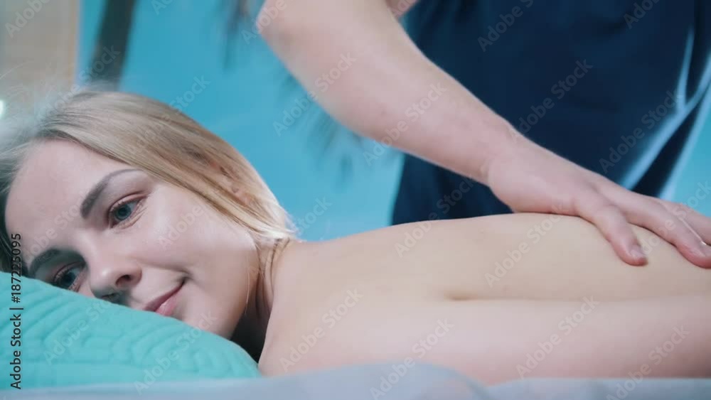 Man's hands on the back of the girl in massage parlor Man's hands on the back of the girl in massage parlor