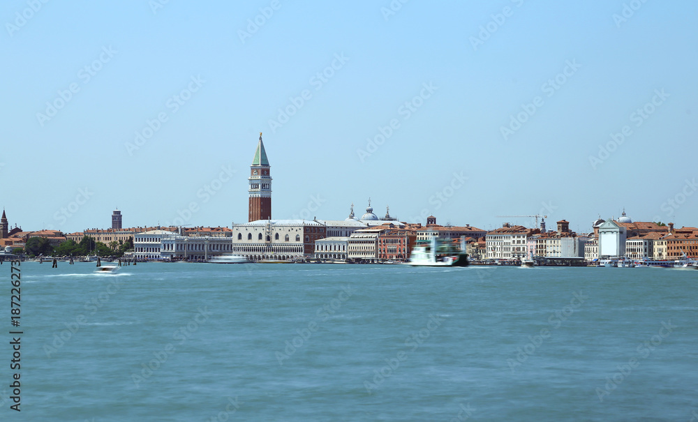 View of the island of venice with ancient palaces and bell towers with long exposure time and the wake of the movement of ships on the Venetian lagoon