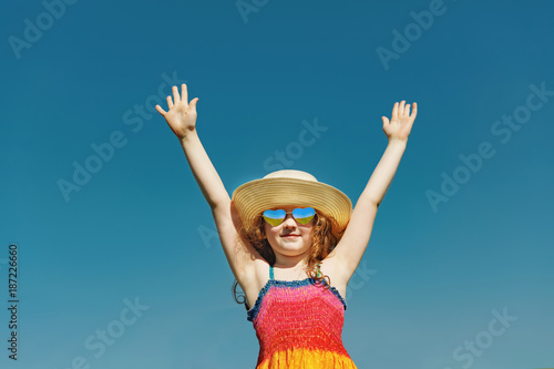 Cute little girl with sunglasses hand up and enjoy fresh air