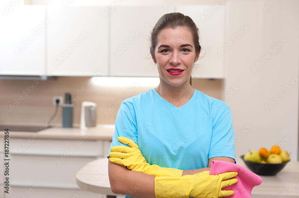 The cleaning is over. Beautiful young woman housewife in rubber gloves standing in kitchen after cleaning The cleaning is over. Beautiful young woman housewife in rubber gloves standing in kitchen after cleaning