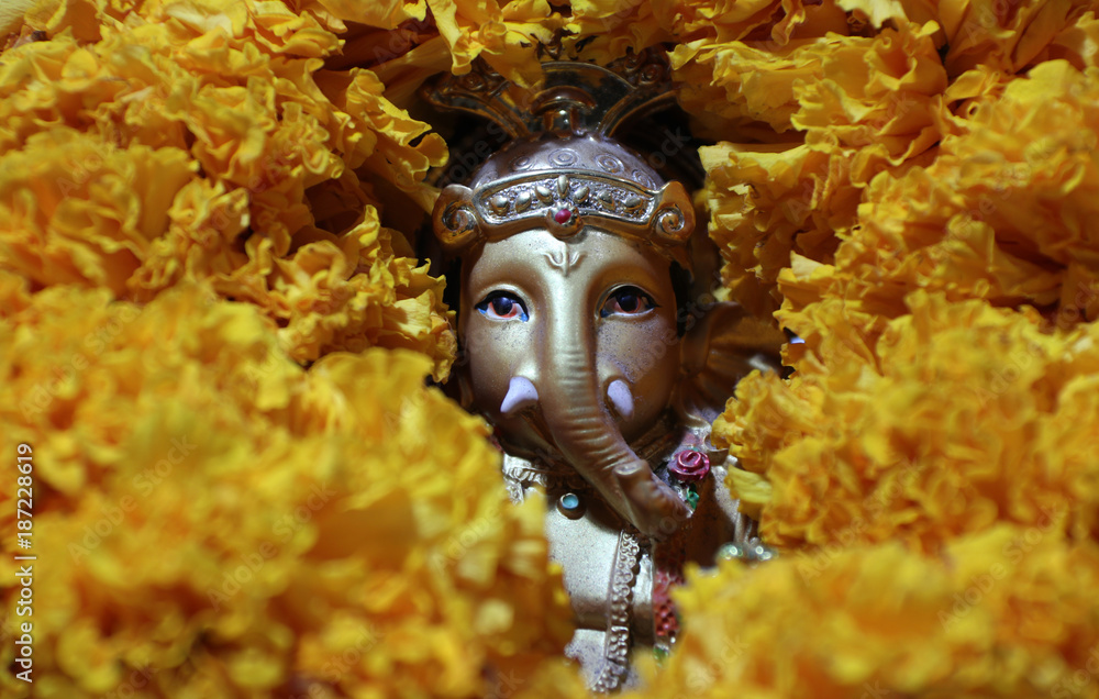 Ganesha made from brass among of yellow marigold flower, the son of Uma