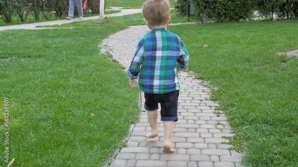 Slow motion video of cute 2 years old barefoot toddler boy runnin at park Slow motion video of cute 2 years old barefoot toddler boy runnin at park
