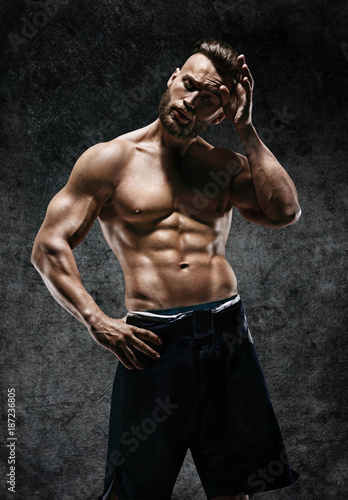 Tired athletic man wiping sweat his hand. Photo of man with perfect body after training. Strength and motivation