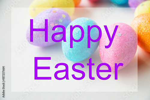 Pile of colorful eggs, candy and toys with Happy Easter card over white